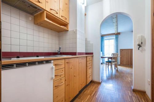 una cocina con armarios de madera y una mesa en una habitación en Lindenhof Apt 7, en Vandoies