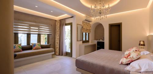 a bedroom with a bed and a couch and a chandelier at Zephyros Hotel in Kamari