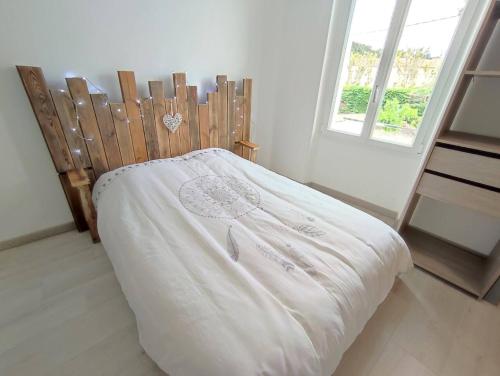 a bedroom with a bed with a wooden headboard and a window at Maison au calme avec parking proche centre-ville in Orange