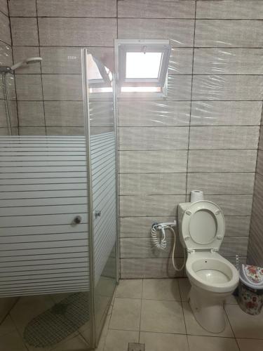 a bathroom with a toilet and a shower with a window at Akko Gate Hostel in Acre