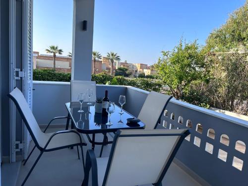 a table and chairs on a balcony with a bottle of wine at La Casa di Leone - Casa GIO in Svoúrou Metókhion