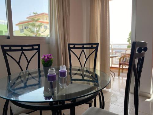 uma mesa de vidro e cadeiras numa sala de estar em Seaside apartment with balcony em Las Galletas