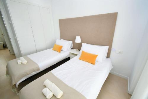 Cette chambre comprend 2 lits avec des oreillers blancs et orange. dans l'établissement Casa Kerr - Luxury Apt - Sleeps 9 - Los Boliches, à Malaga