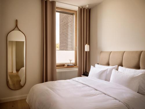 a bedroom with a large white bed and a mirror at 1884 Norderney in Norderney