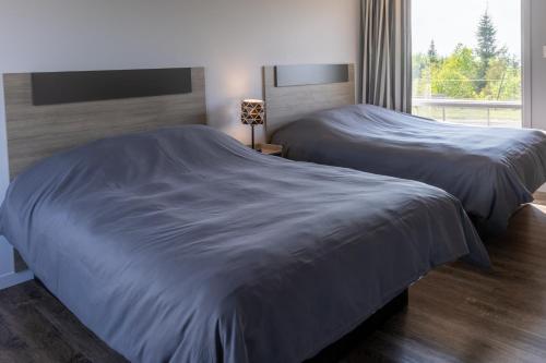 two beds in a bedroom with a large window at Le Fraser Motel in Rivière-du-Loup