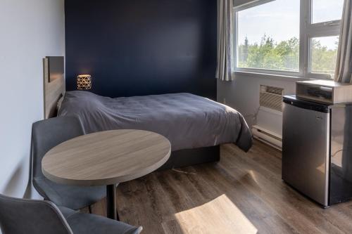 1 dormitorio con cama, mesa y ventana en Le Fraser Motel, en Rivière-du-Loup