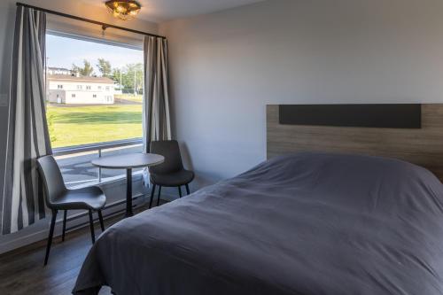 1 dormitorio con cama, mesa y ventana en Le Fraser Motel, en Rivière-du-Loup