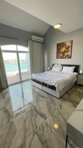1 dormitorio con cama y ventana grande en درة العروس فيلا الذهبي 38 en Durat  Alarous