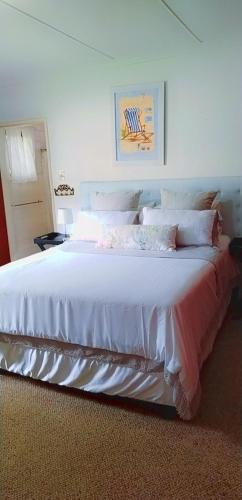 1 dormitorio con 1 cama blanca grande con sábanas blancas en Nzima BnB, en Estcourt