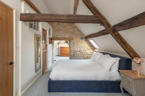 a bedroom with a white bed and a stone wall at Shockerwick Cottage in Bath