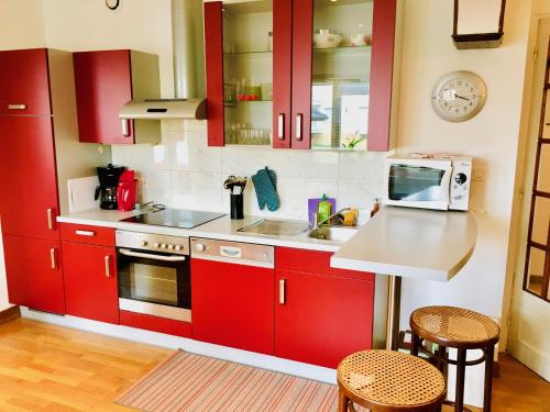 La cuisine est équipée de placards rouges, d'un évier et d'un comptoir. dans l'établissement Gîte City Relax, entre nature et centre-ville, à Colmar