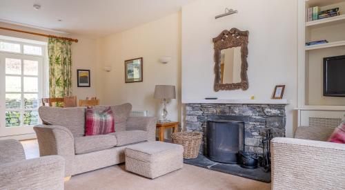 een woonkamer met stoelen en een open haard bij Forge Cottage in Rusland