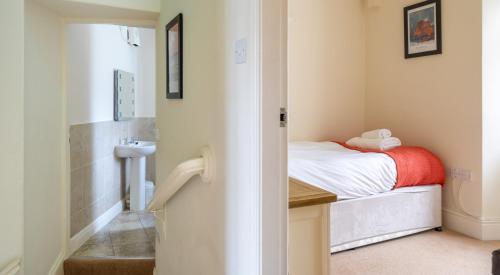 a small bedroom with a bed and a sink at Forge Cottage in Rusland