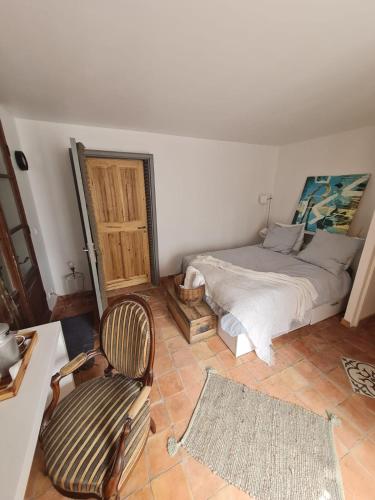 een slaapkamer met een bed en een stoel bij Chambre d'Hôtes in Volonne