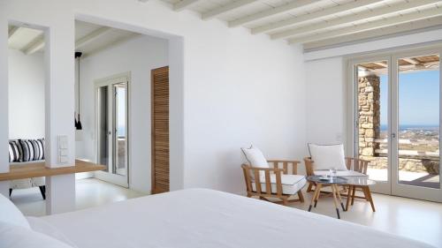 a bedroom with a bed and a table and chairs at Home of the Gecko - Mykonos Town in Megali Ammos