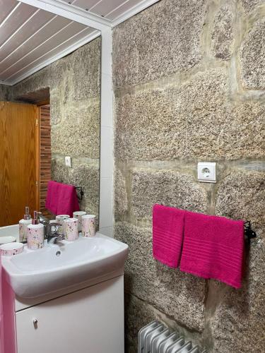 a bathroom with a sink and pink towels at CASA DA QUELHA in Soajo