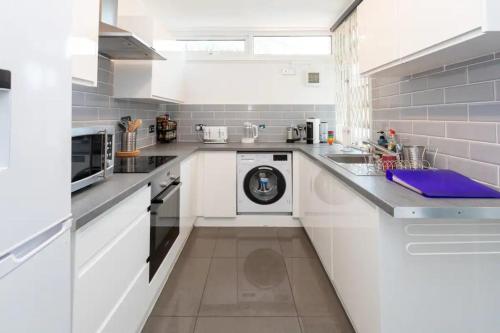 a white kitchen with a washing machine in it at Spacious & Welcoming 4BD House - Kennington in London