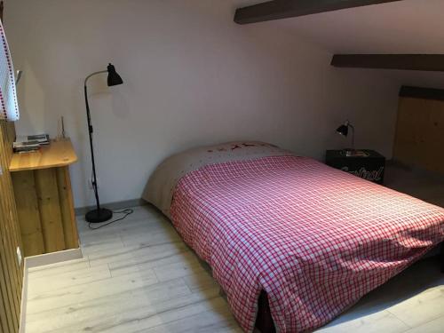 sypialnia z łóżkiem z czerwonym i białym kocem w obiekcie Gîte Le Buron w mieście Chazelles
