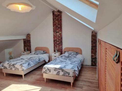 deux lits dans une chambre avec un mur de briques dans l'établissement La Citadine, maison avec jardin…, à Soissons