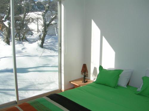 a bedroom with a green bed and a large window at Cabañas Ecobox Andino in Las Trancas