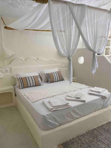 a white bed with white curtains and towels on it at Traditional Syrma Nikos in Klima