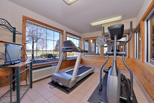einen Fitnessraum mit einem Laufband, einem Schreibtisch und einem TV in der Unterkunft Kelly Inn Billings in Billings