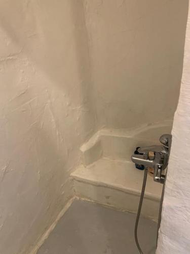 a corner of a bathroom with a sink and a hose at Traditional Syrma Nikos in Klima
