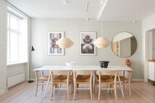 una sala da pranzo con tavolo, sedie e specchio di 2BR in Vibrant & Colourful Nyhavn Copenhagen City a Copenaghen