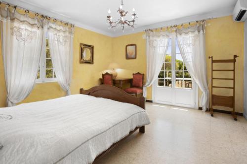 um quarto com uma cama, janelas e um lustre em Villa Regina 500 métres de la plage em La Garonnette-Plage