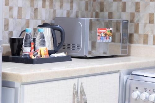 a kitchen counter with a microwave and bottles of water at Mooj served Apartments موج للشقق المخدومه in Dammam