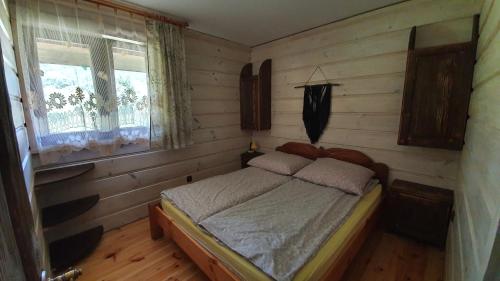um quarto com uma cama num quarto com pisos em madeira em Bieszczady Domki w Dolinie Sanu em Lutowiska