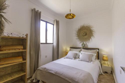 a bedroom with a bed with white sheets and a window at Villa Essaouira petit déjeuner compris in Essaouira