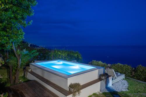a swimming pool at night with the ocean in the background at Villa Marilu Praiano in Praiano
