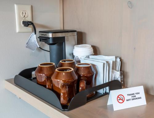 a coffee maker and three coffee cups on a shelf at Crosby Lofts in Crosby
