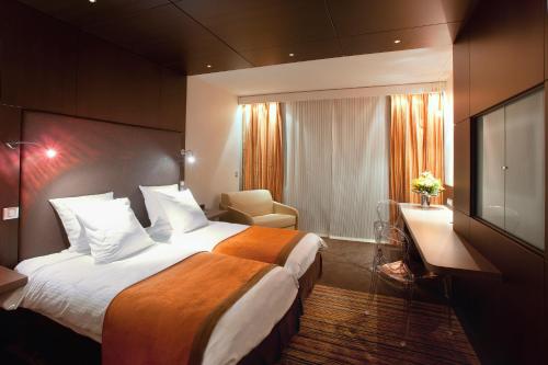 Habitación de hotel con cama grande y TV en Hôtel & Spa Vatel en Nimes