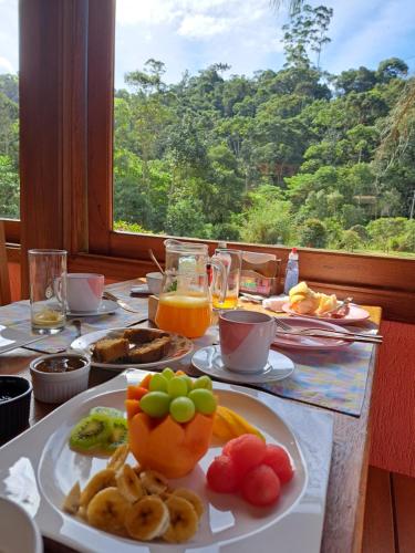a table with a plate of food with fruit on it at Pousada Vale da Cachoeira in Visconde De Maua