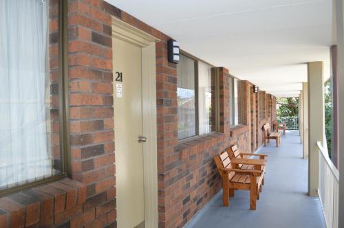 a brick hallway with two chairs and a door at Best Western Parkside Motor Inn in Coffs Harbour