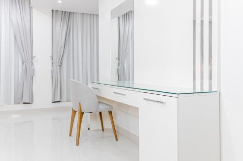 a white desk with a glass top and a white chair at Mooj served Apartments موج للشقق المخدومه in Dammam