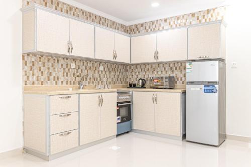 a kitchen with white cabinets and a refrigerator at Mooj served Apartments موج للشقق المخدومه in Dammam
