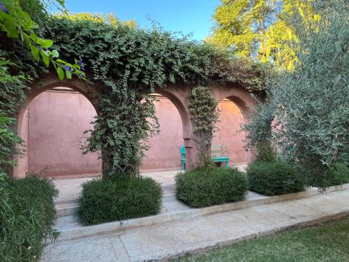 a garden with two arches with plants and a bench at Villa #1 ‘Rosalie’ in Marrakech