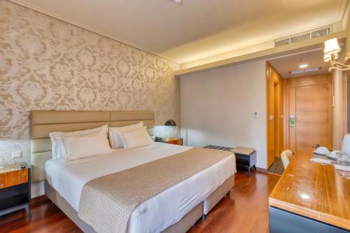 a hotel room with a large bed and a desk at Hotel Lis Batalha in Batalha
