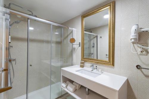 bagno con doccia, lavandino e specchio di Hotel Lis Batalha a Batalha
