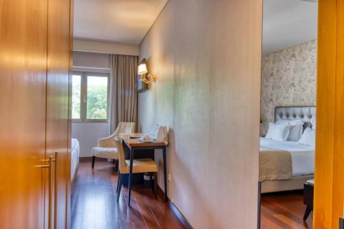 a hotel room with a bed and a desk and a table at Hotel Lis Batalha in Batalha