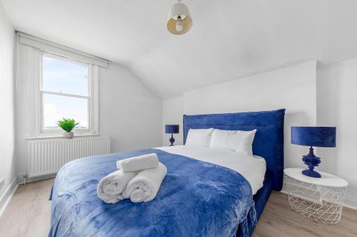 a bedroom with a blue bed with towels on it at The Earl - Hampstead Heath in London