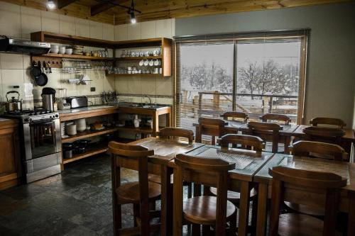 a kitchen with wooden tables and chairs and a large window at Refugio Ecobox Andino in Las Trancas