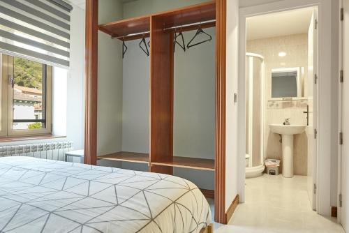 una camera con letto e un bagno con lavandino di HOSTAL FONTAÑAN a La Pola de Gordón