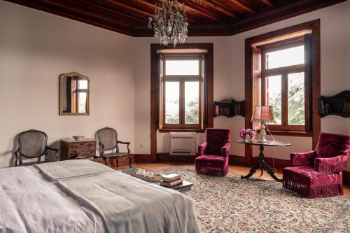 a bedroom with a bed and chairs and a chandelier at Chalet Ficalho in Cascais