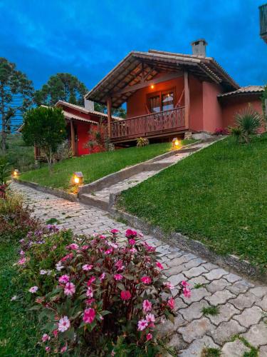 a house with a balcony and flowers in front of it at Pousada Vale da Cachoeira in Visconde De Maua