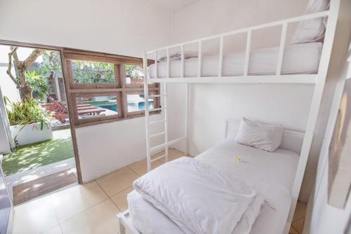 1 Schlafzimmer mit 2 Etagenbetten und einem Fenster in der Unterkunft The Island Bali in Seminyak