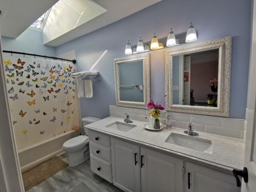 a bathroom with two sinks and a toilet and a mirror at Diana's Beauty House in Charlottetown